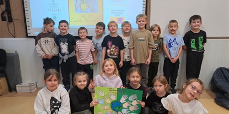 Powiększ grafikę: Dzieci z klasy 1c stoją przed tablicą z plakatem "Tolerancja" 