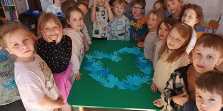 Powiększ grafikę: Dziec z grupy przedszkolnej wykonali plakat z niebieskich papierowych dłoni.