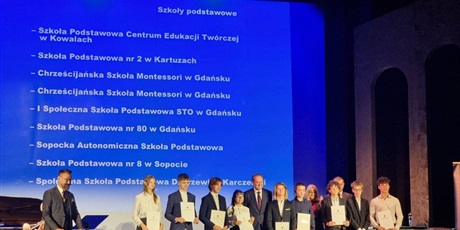 Powiększ grafikę: wyrożnieni uczniowie stoją razem na podium