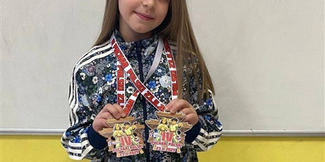 Powiększ grafikę: Dziewczynka prezentuje zdobyte medale.