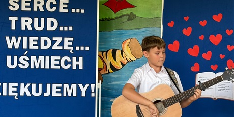 Powiększ grafikę: Chłopiec gra na gitarze.