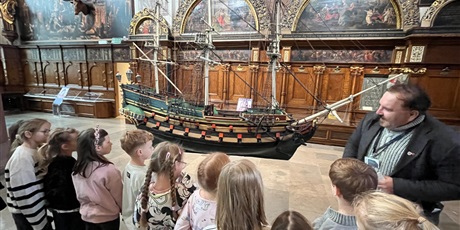 Powiększ grafikę: Dzieci z kl.1b uważnie słucchają opowieści przewodnika w sali Dworu Artusa.