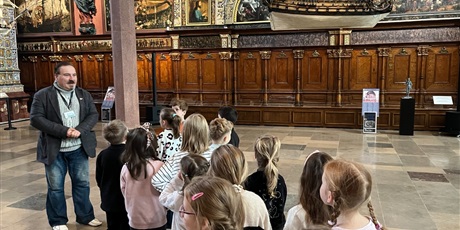 Powiększ grafikę: Dzieci z kl.1b uważnie słucchają opowieści przewodnika w sali Dworu Artusa.