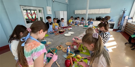 Powiększ grafikę: Dzieci przy wspólnym stole w Kuchcikowie przygotowują przekąskę.