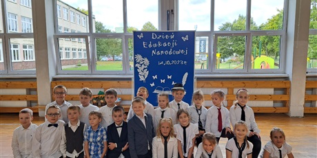 Powiększ grafikę: Dzieci klęczące przed tablicą z napisem "Dzień Edukacji Narodowej"