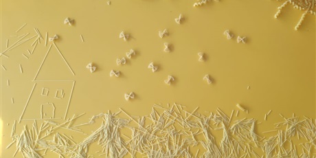 Powiększ grafikę: Łąka z domem zrobiona z makaronu na żółtym tle